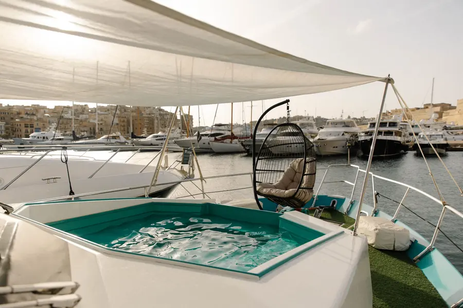 Plunge pool and hanging chair on the bow with the marina and Birgu behind