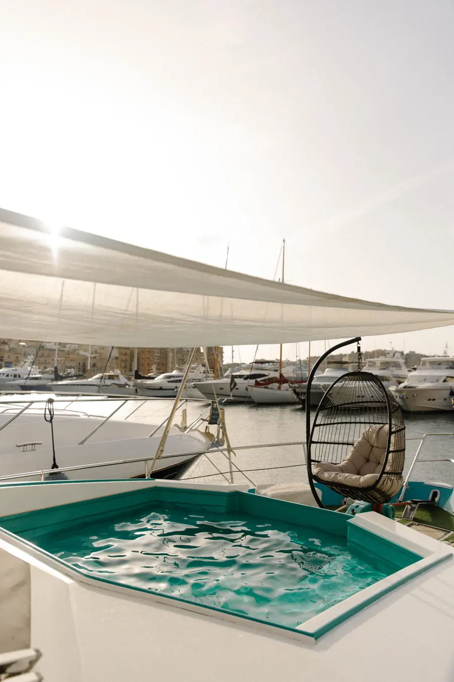 Bow plunge pool and hanging chair under a sun sail aboard Canaima at golden hour