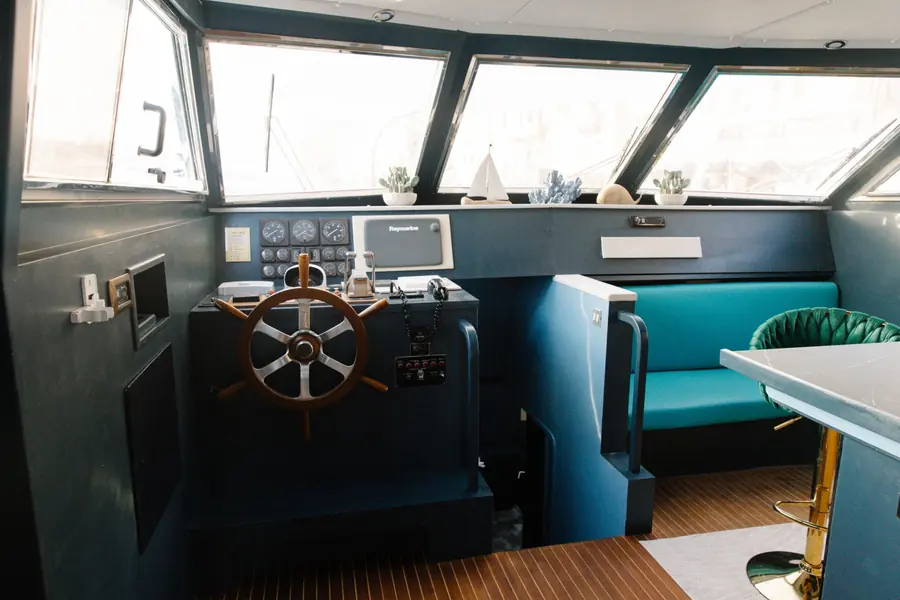 Classic wooden ship's wheel at the helm station next to the dinette