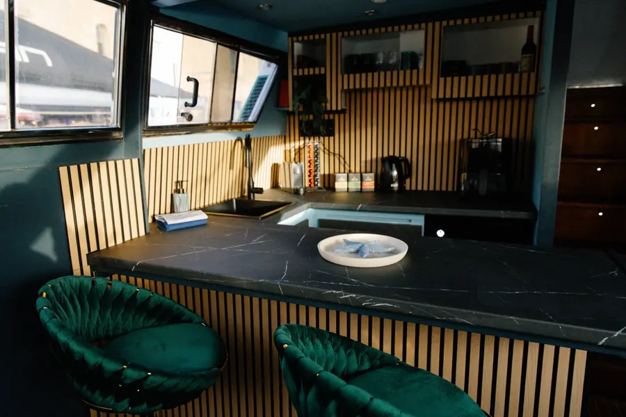 Kitchen bar with green velvet stools and oak slat wall