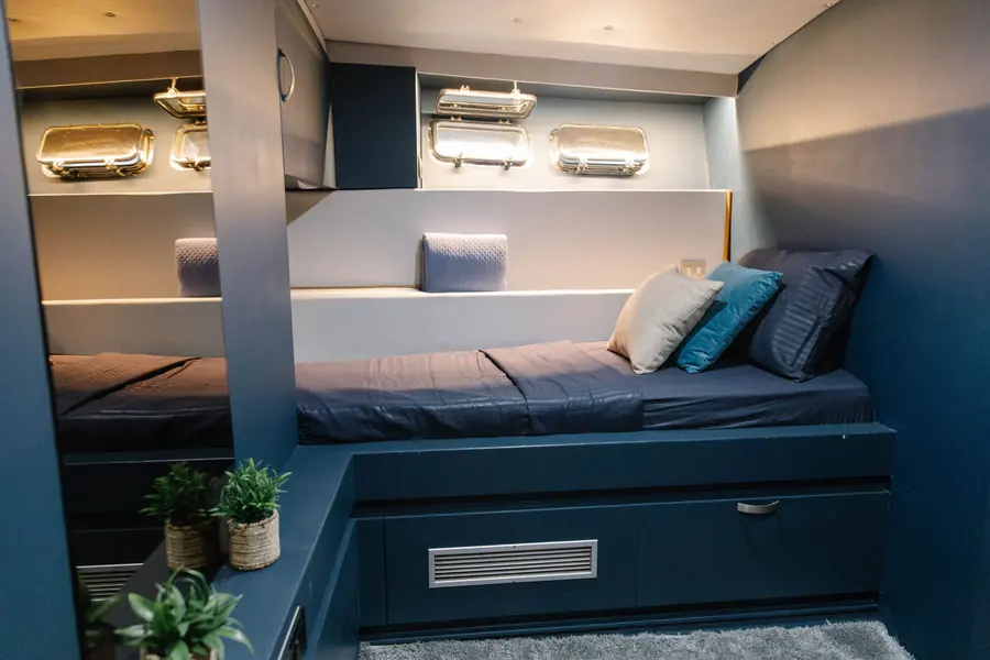 Cabin with single bed, cushions and brass portholes