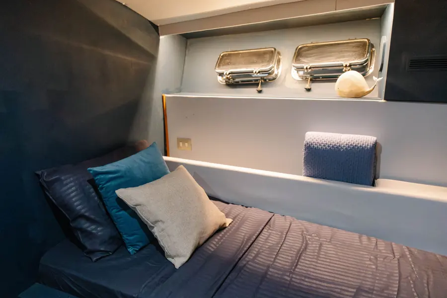 Bed with cushions below two brass portholes