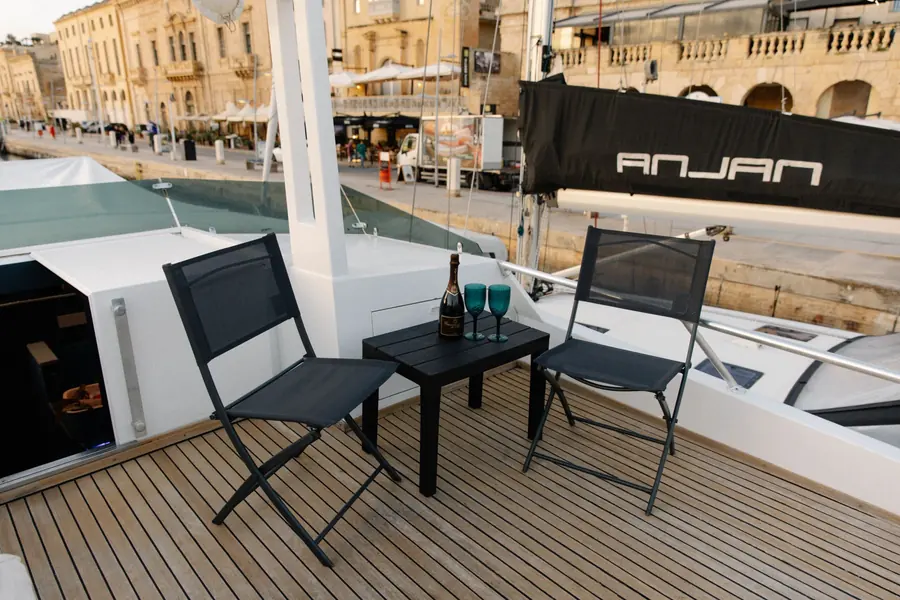 Flybridge with table, two chairs and a bottle on ice above the Birgu waterfront